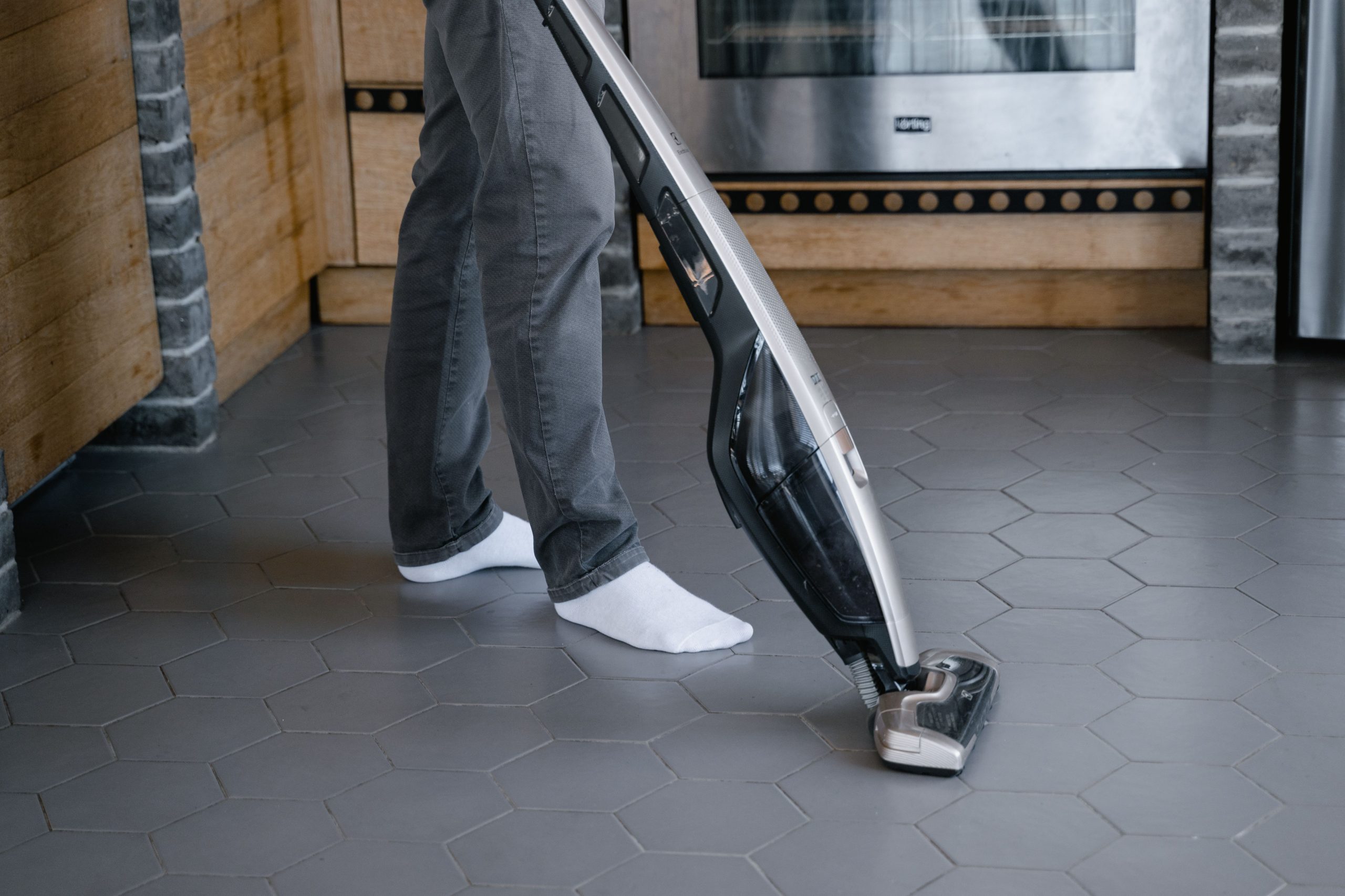 Personne nettoyant un carrelage avec un aspirateur moderne