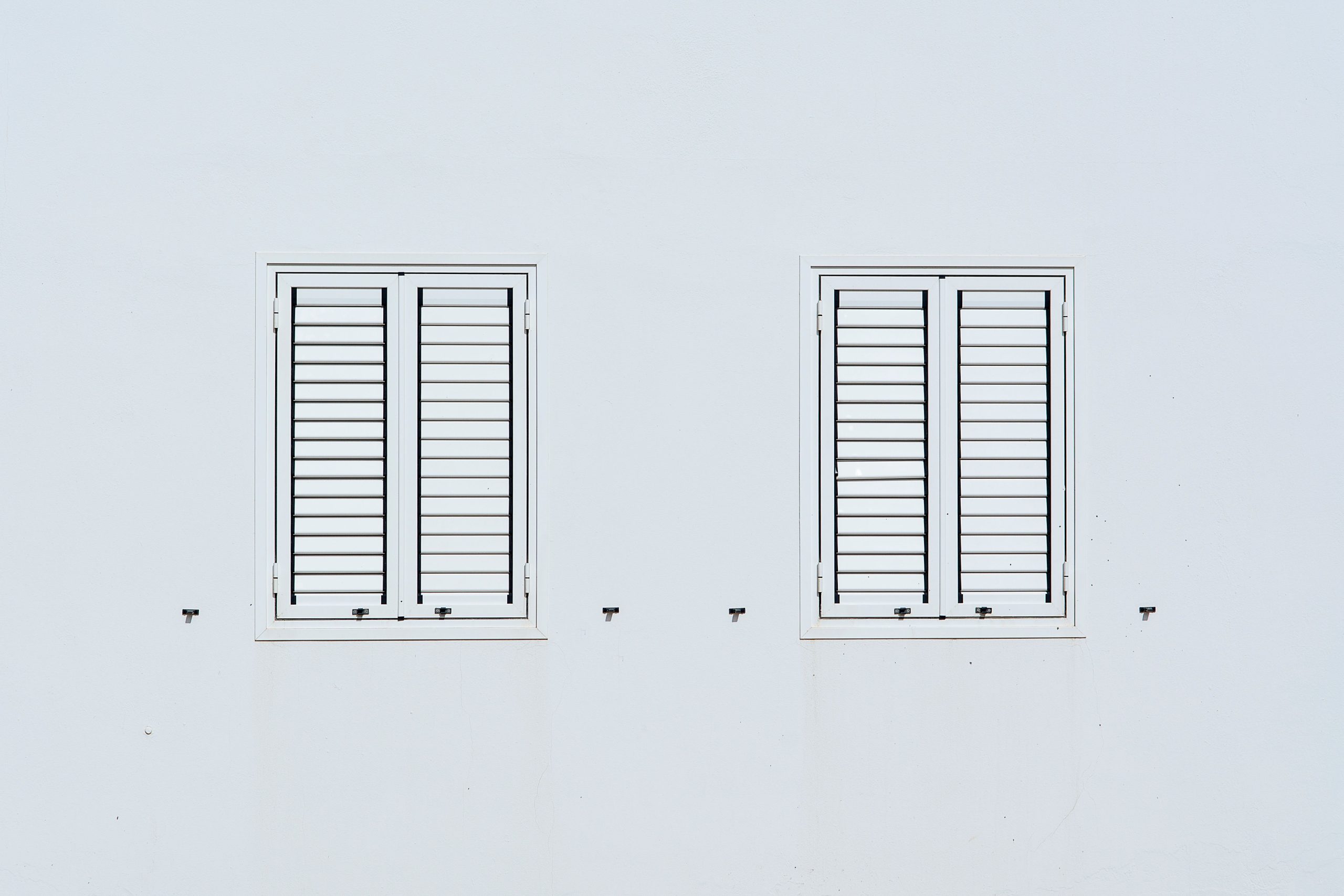 Deux fenêtres à volets sur mur blanc