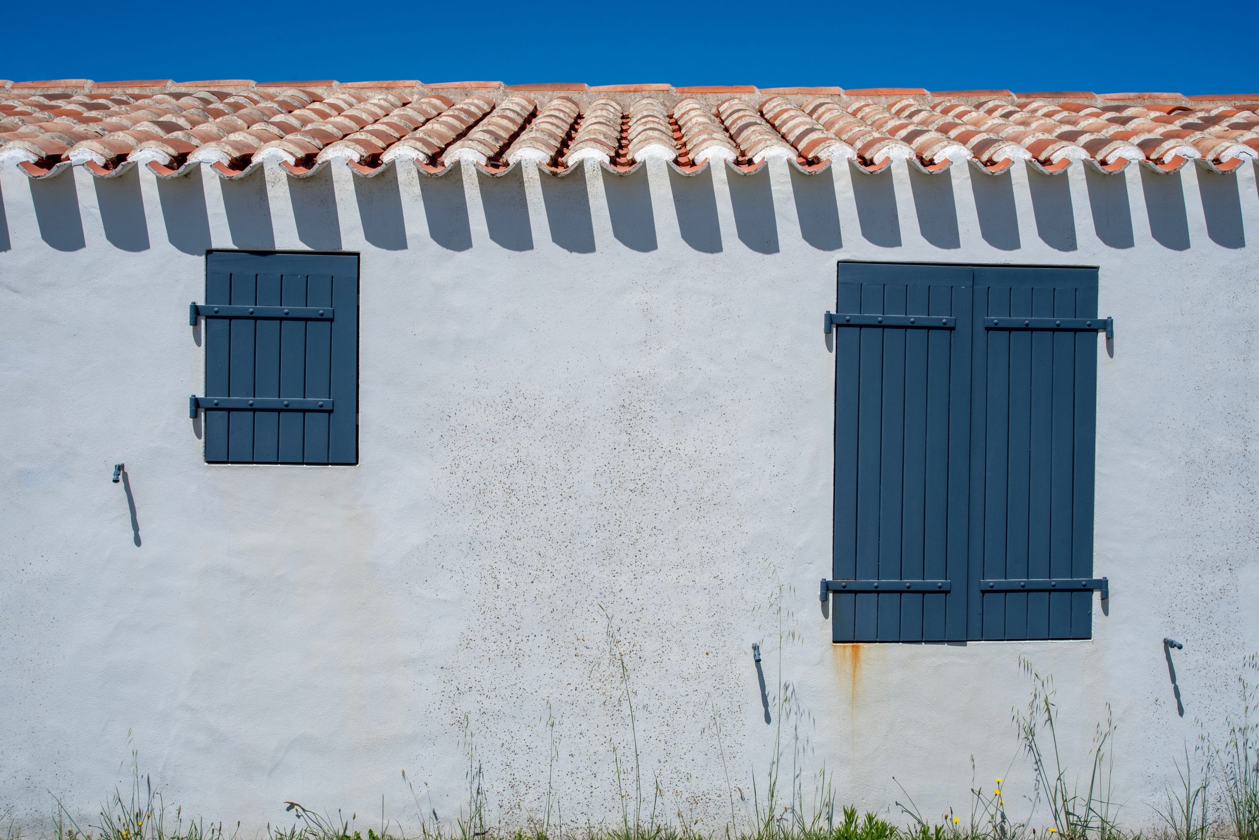 Façade aux volets bleus et toit en tuiles